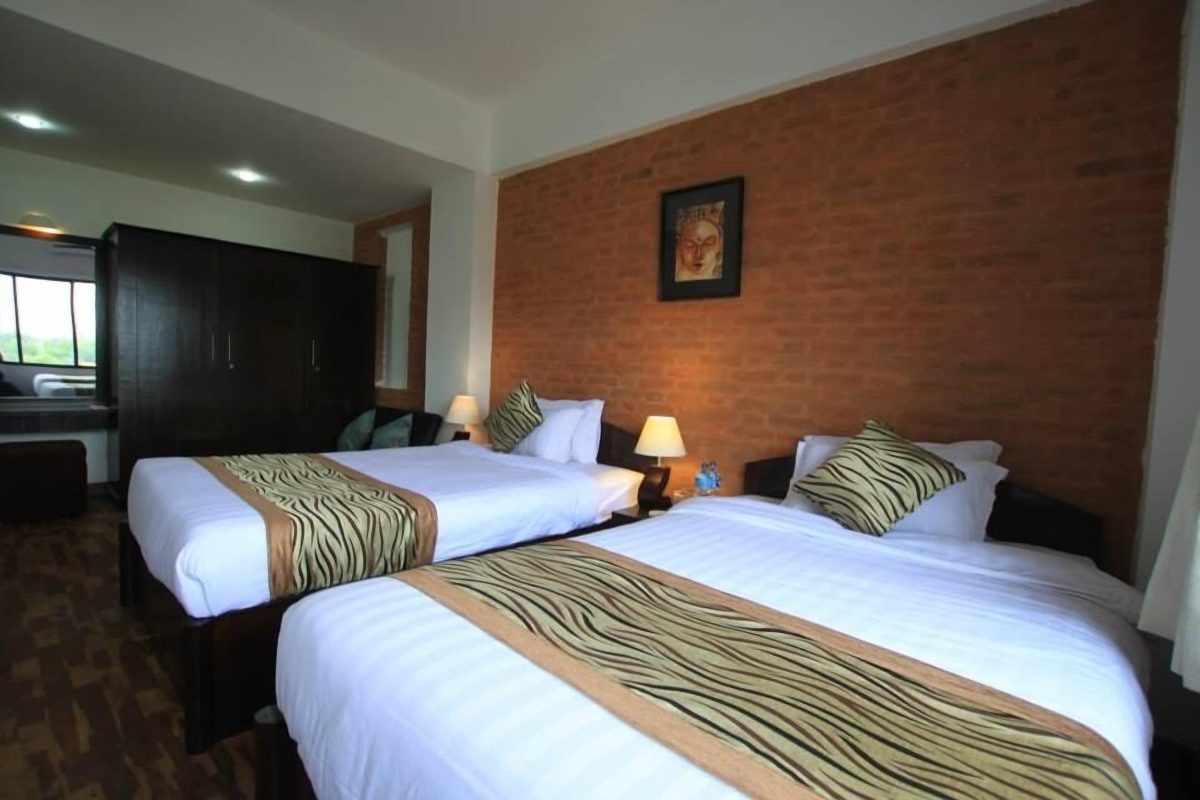 Habitación de hotel con dos camas, una pared de ladrillo y un cuadro enmarcado.