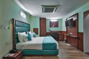Una habitación de hotel con cama, escritorio y televisor.