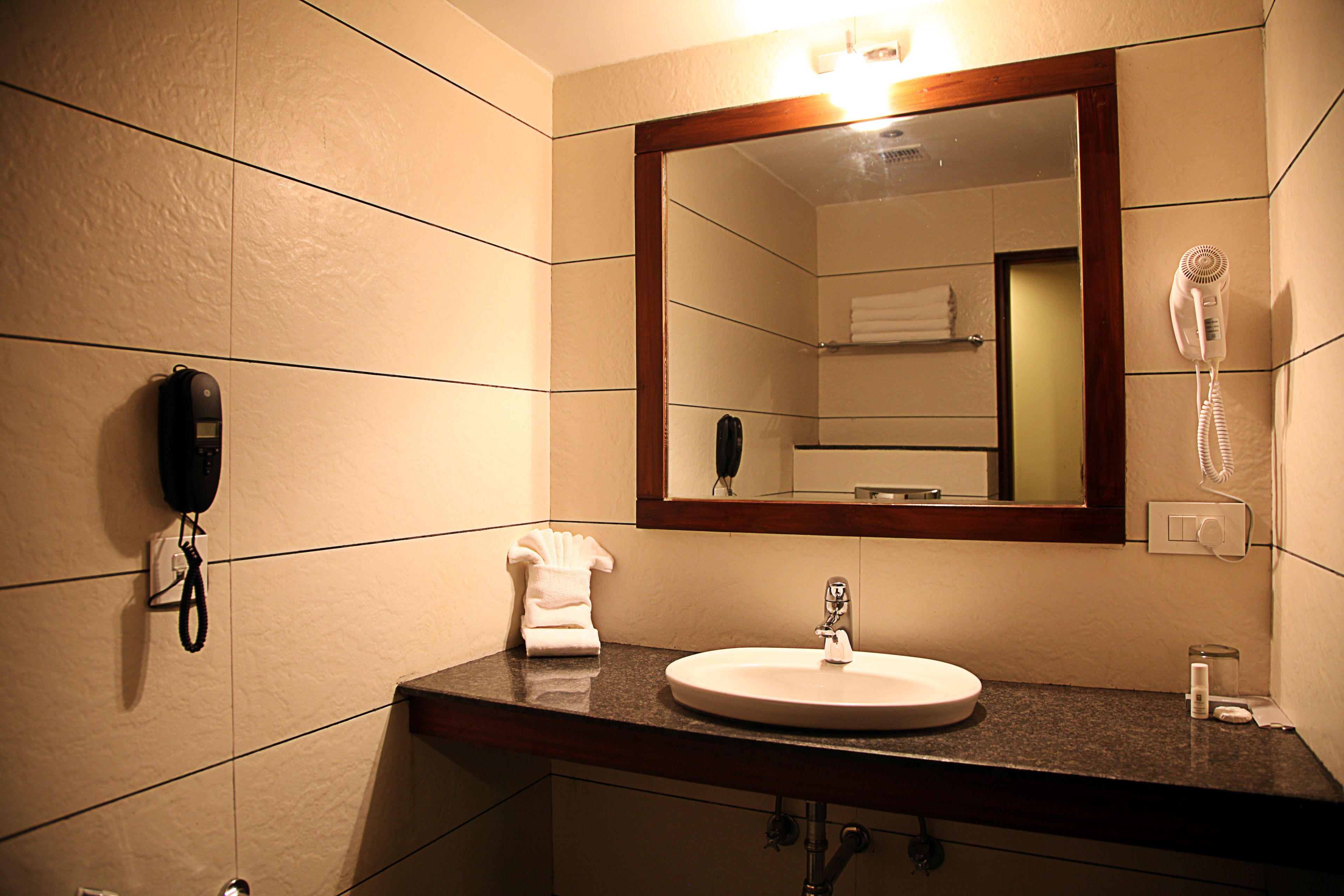 A bathroom with a sink, mirror, towel rack, and a hairdryer.