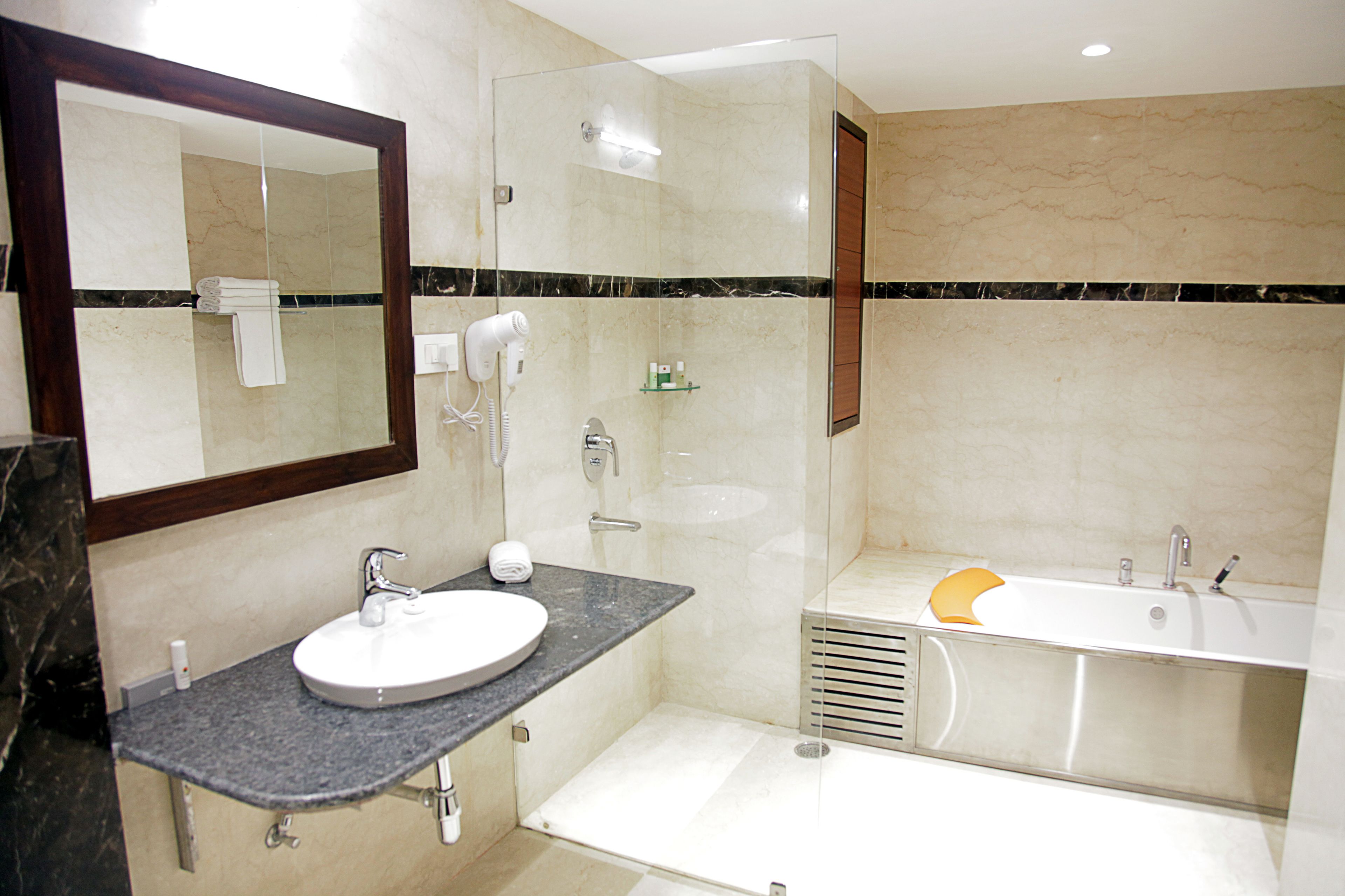 Une salle de bain moderne avec un lavabo en marbre, une douche à parois de verre et une grande baignoire.