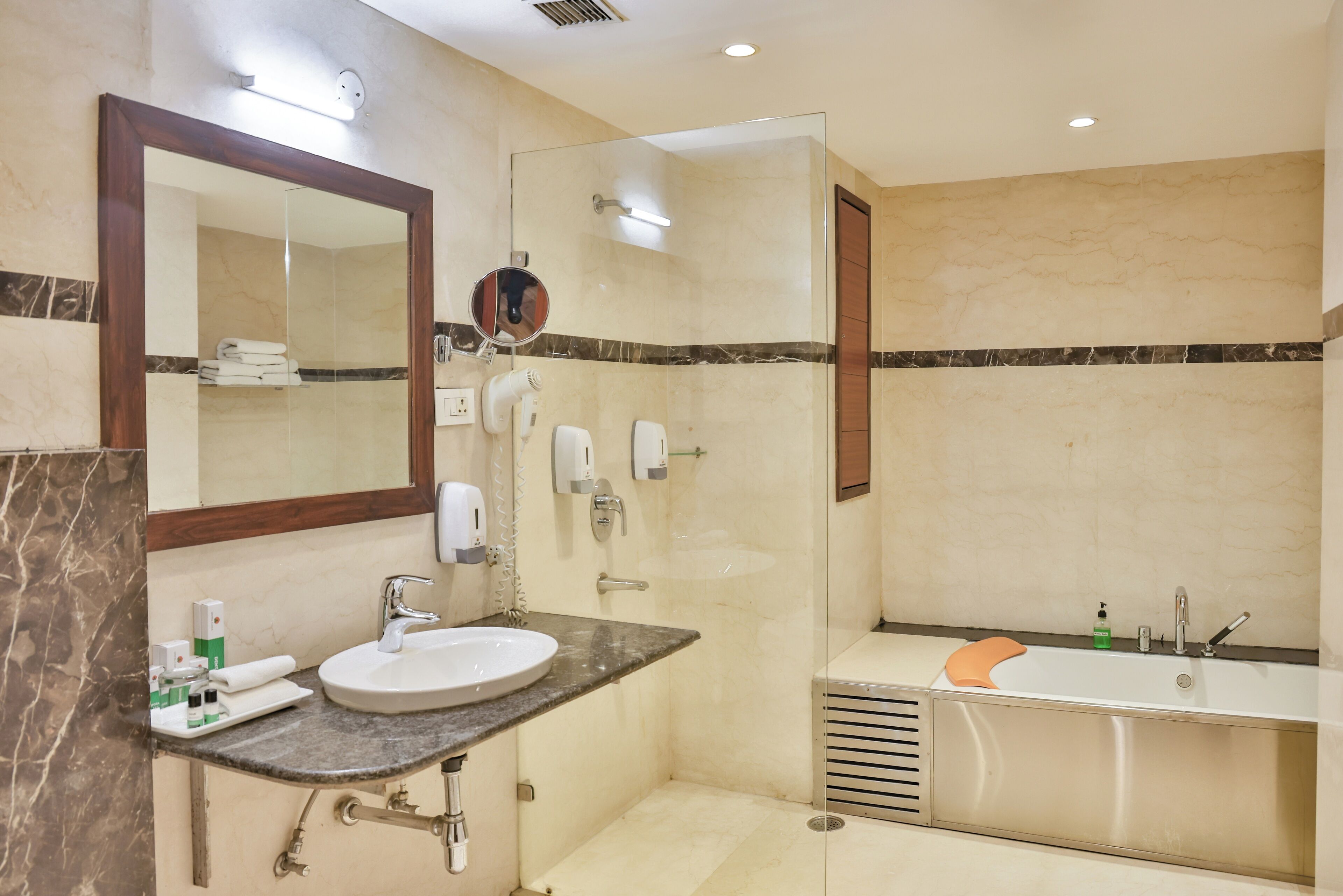 Un baño moderno con un lavabo de mármol, ducha con mampara de vidrio y bañera independiente.
