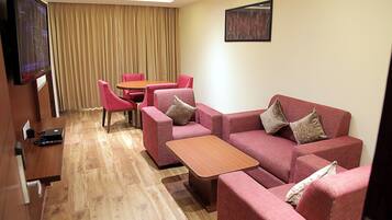 Une chambre d’hôtel comprenant un canapé, une petite table, un téléviseur et une table à manger avec des chaises.