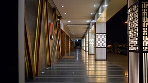 A well-lit corridor with modern lighting fixtures and a clean, reflective floor. - Hotel Cama (Mohali)