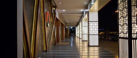Un couloir bien éclairé, doté de luminaires modernes et d’un sol propre et réfléchissant.