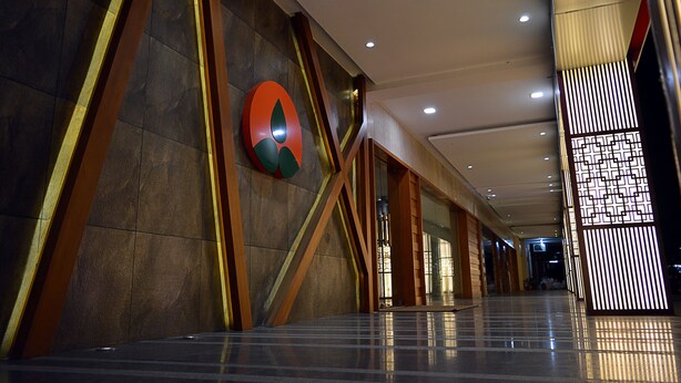 A modern interior with a large logo on the wall, a polished floor, and a decorative panel. - Hotel Cama (Mohali)