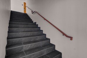 Un escalier avec des marches noires et une rampe en bois.