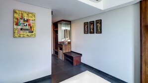 A hallway with a wooden bench, a mirror, and artwork on the walls. - Palette Hotel Seminyak (Seminyak)