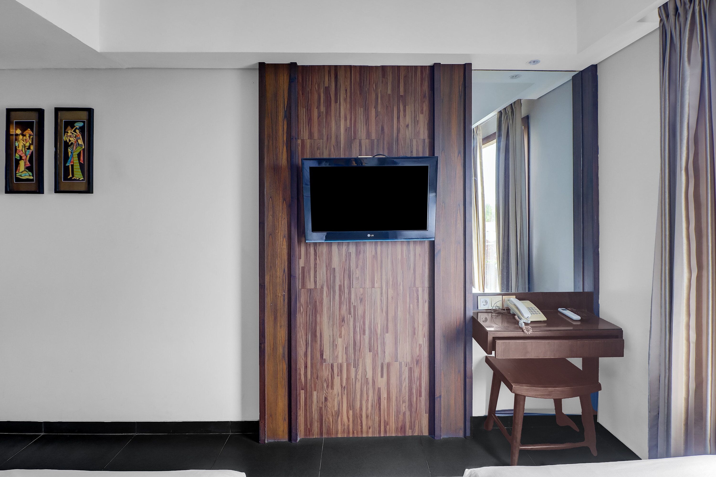 Habitación de hotel con una pared de acento de madera, un televisor de pantalla plana montado en ella, un escritorio con teléfono y una silla.