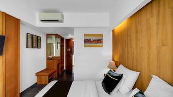 A hotel room with a bed, a desk, a mirror, and a painting on the wall.