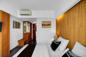 Une chambre d’hôtel avec un lit, un bureau, un miroir et un tableau accroché au mur.