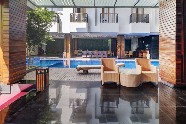 A modern outdoor pool area with lounge chairs, a wooden deck, and a glass balustrade. - Palette Hotel Seminyak (Seminyak)