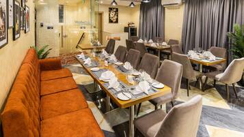 A restaurant with a long wooden table set for dining, cushioned seating, and a modern interior design.