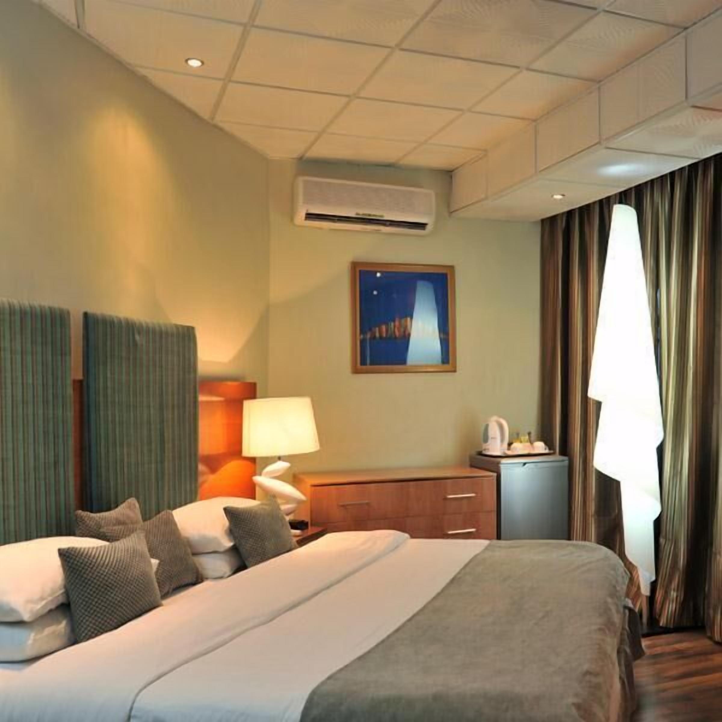 Une chambre d’hôtel avec un grand lit, un bureau, une lampe et un tableau au mur.