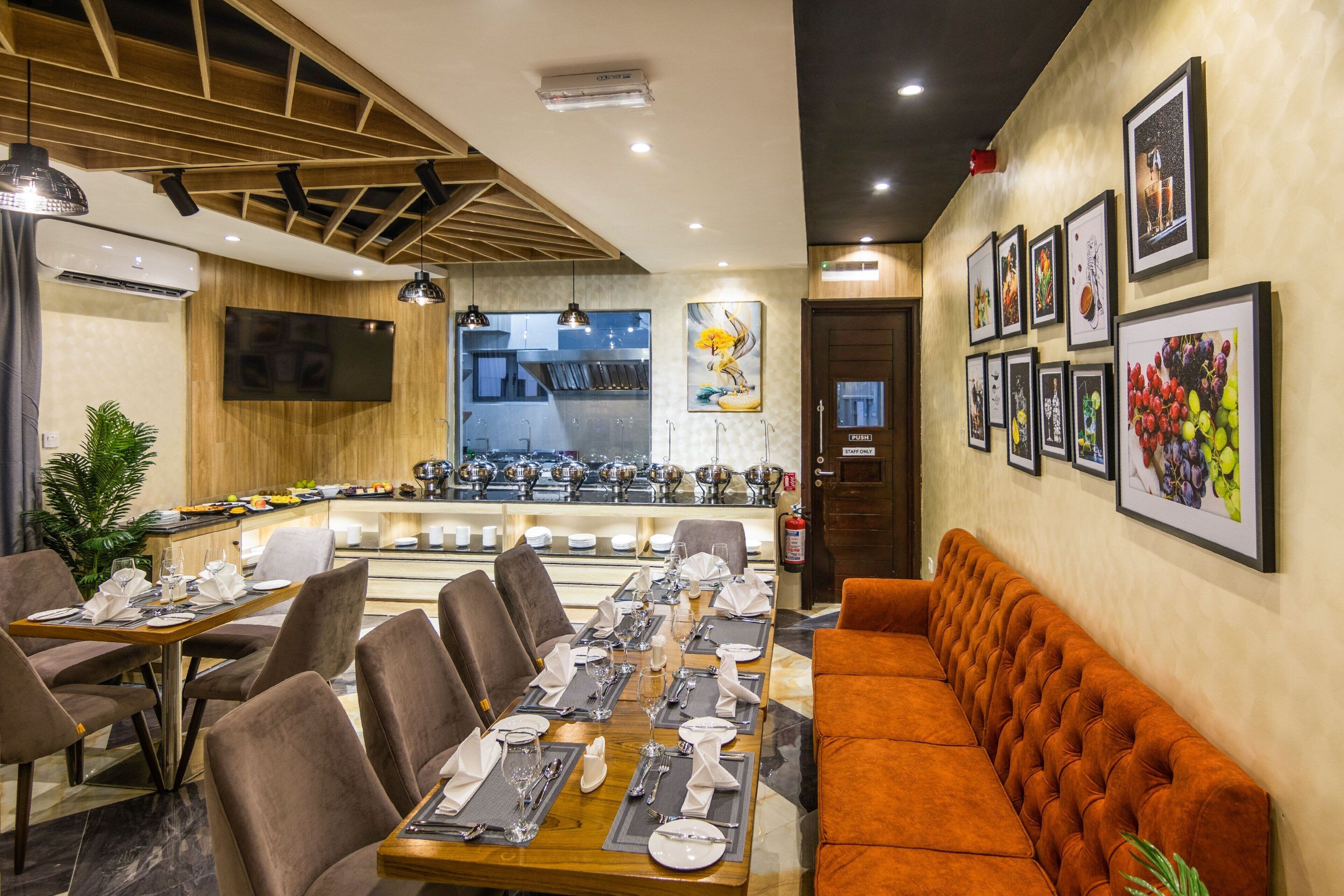 A restaurant with a long dining table set for a meal, a bar area, and a seating area with a sofa.