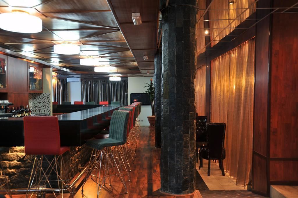 A modern bar area with a long counter, multiple bar stools, and a stone pillar.
