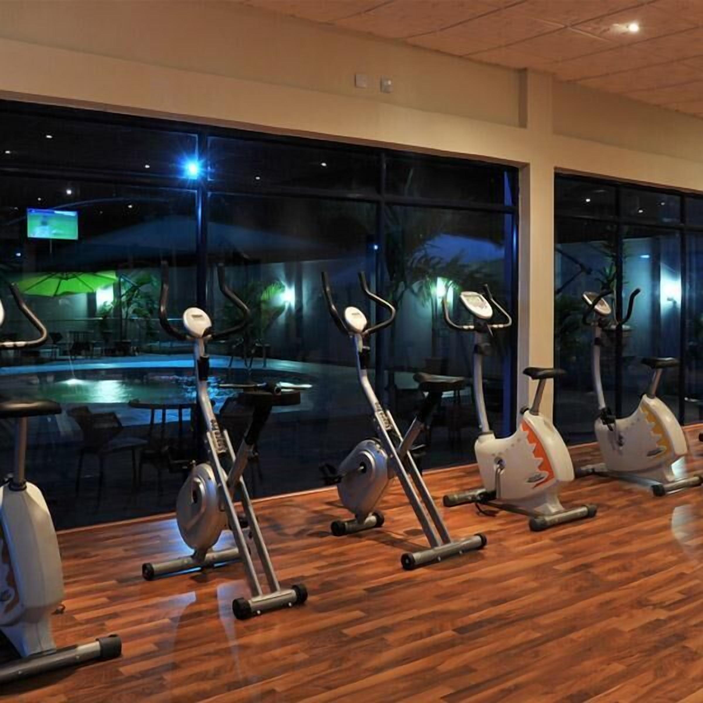 A gym with exercise bikes and a pool visible through the windows.
