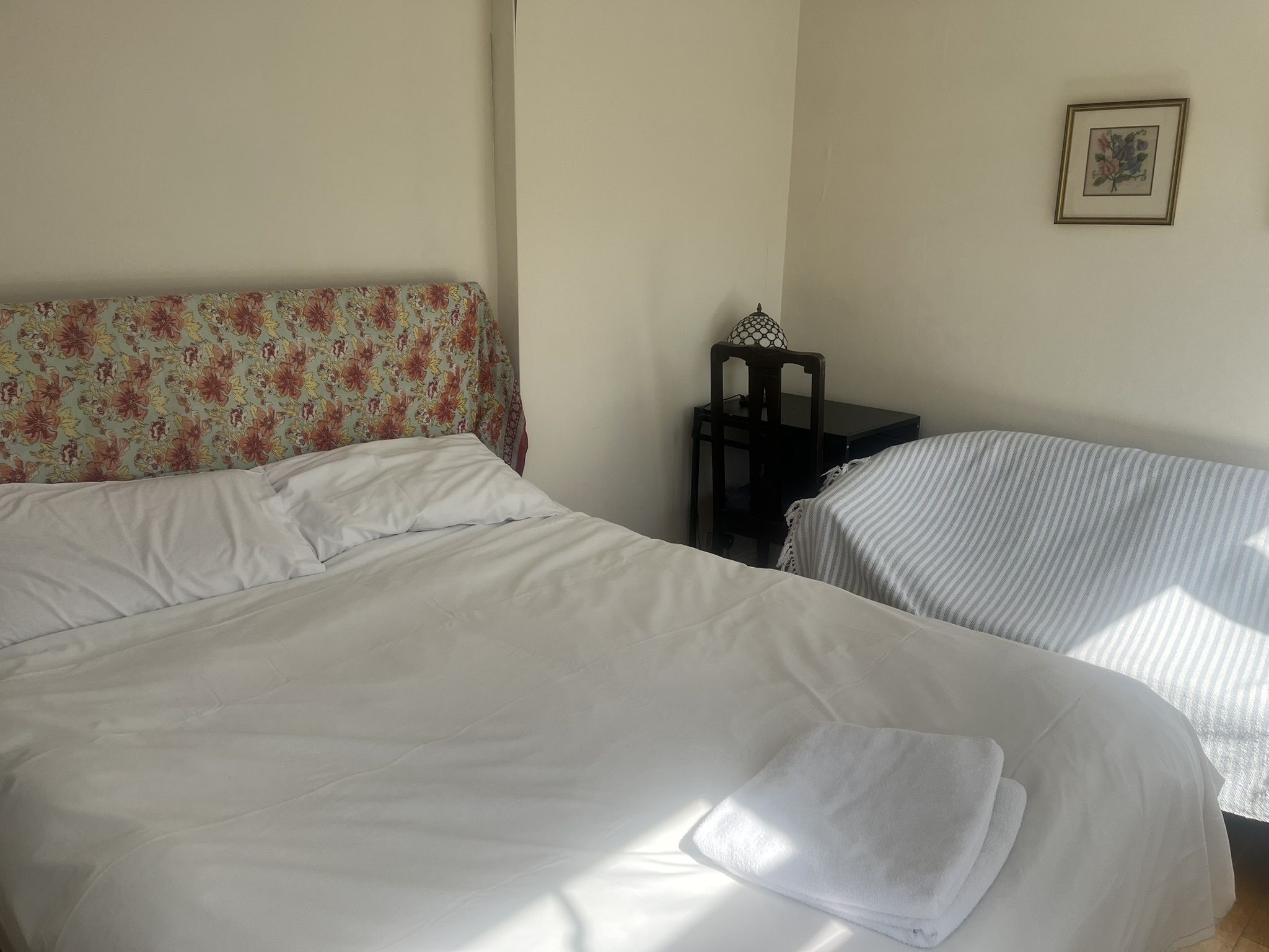Une chambre avec deux lits, dont l’un est doté d’une tête de lit à motifs floraux et l’autre d’une couvre-lit à rayures.