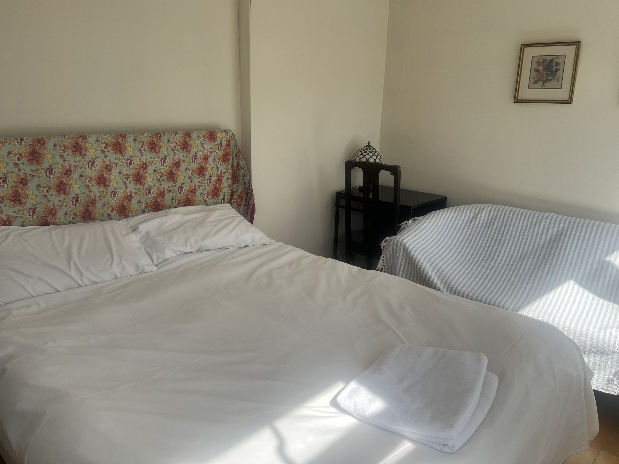 Ein Hotelzimmer mit zwei Betten, einem Sessel, einem kleinen Tisch und einem gerahmten Bild an der Wand.