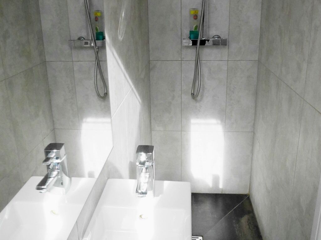 A bathroom with two sinks, a shower, and a towel rack.
