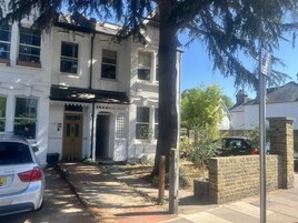 A white building with a yellow door and a number 271 sign.