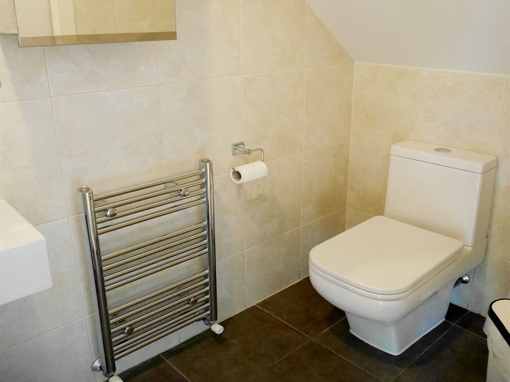 Een badkamer met een toilet, een handdoekhouder en een toiletrolhouder.
