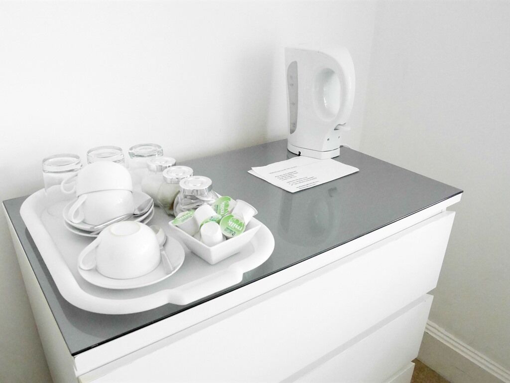 A white tray with tea set and condiments on a gray countertop in a hotel room.