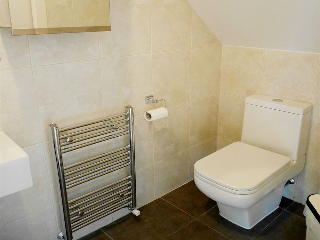 Un baño con inodoro, toallero y dispensador de papel higiénico.