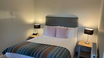 A neatly made bed with a striped blanket, two bedside tables with lamps, and a headboard.