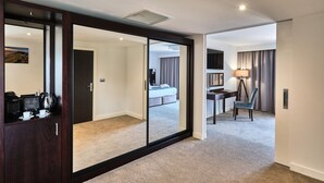 Une chambre d’hôtel dotée d’une grande porte coulissante donnant sur une chambre à coucher, d’un bureau avec une lampe et d’une chaise.