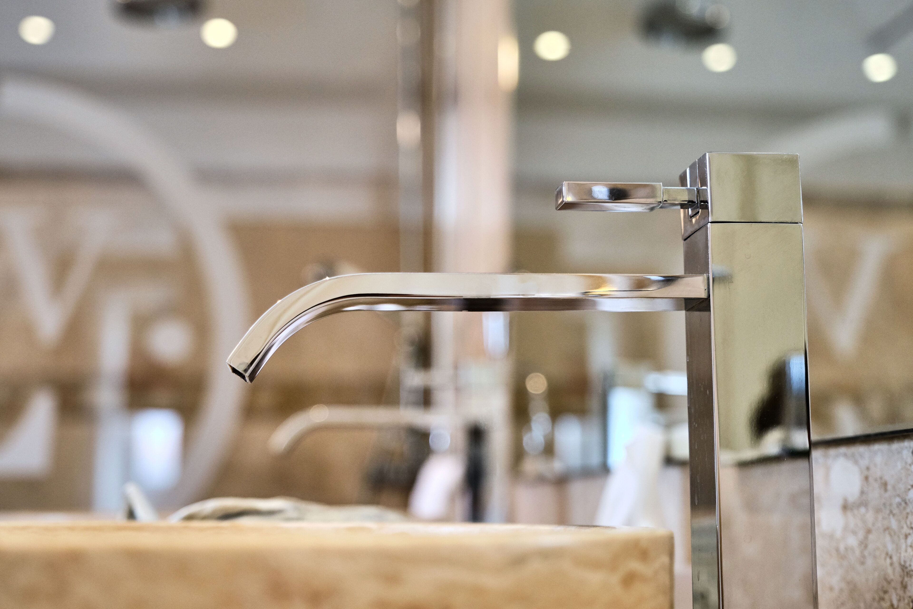 Un baño moderno con grifo cromado y encimera de mármol.