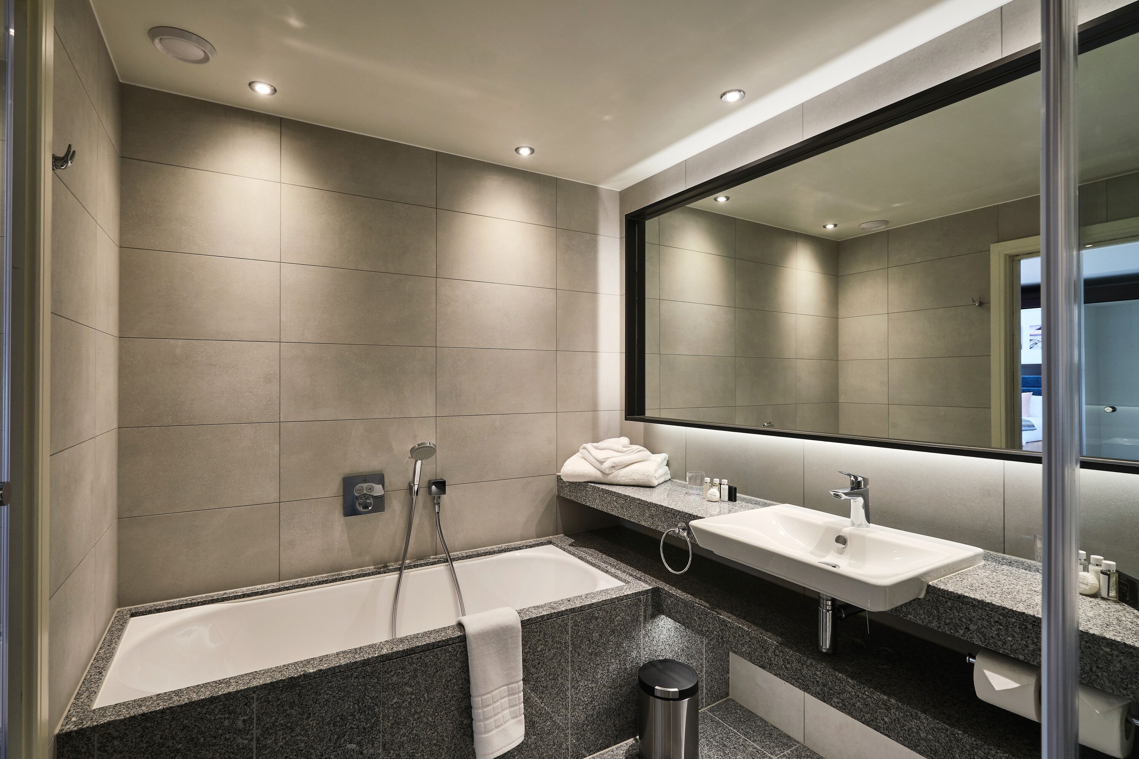 A modern bathroom with a large bathtub, two sinks, and a large mirror.