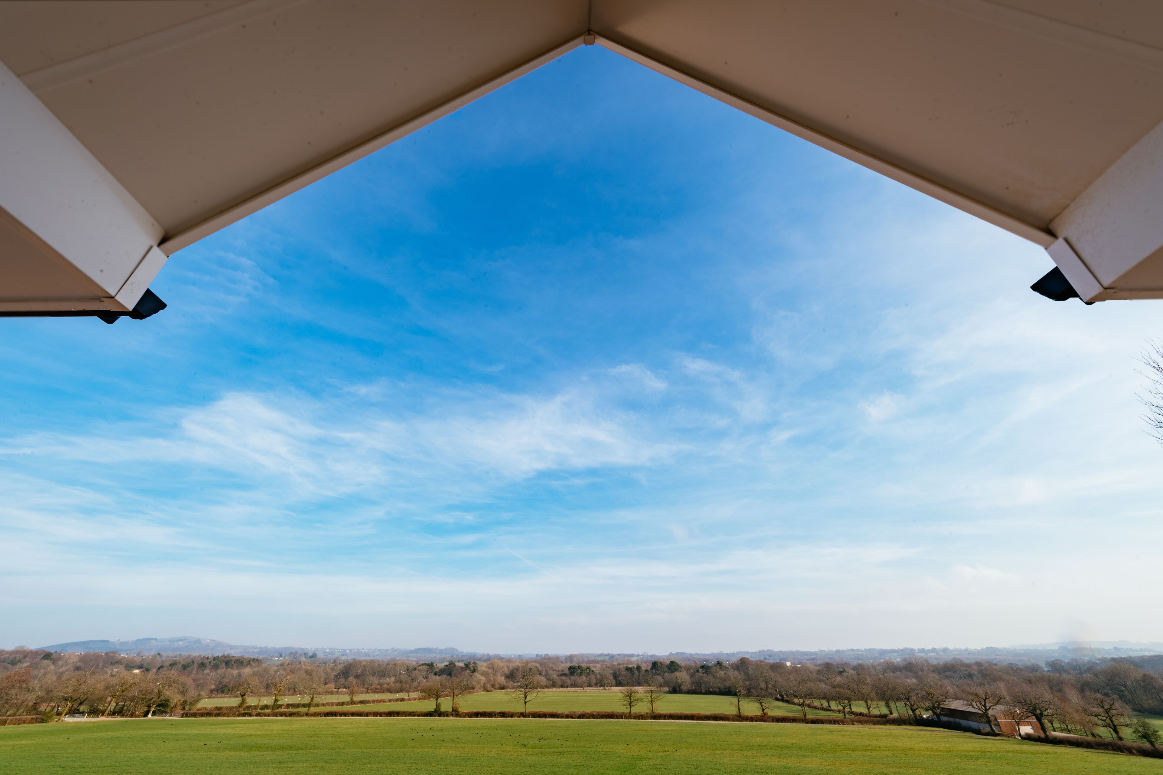 Une vue prise d’en dessous, sous un toit, avec un ciel dégagé et un paysage lointain.