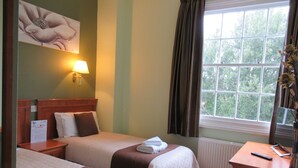 A hotel room with two beds, a nightstand, a desk with a coffee maker, and a window with curtains. - London Inn (Cheltenham)