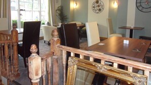 A dining area with wooden furniture, a clock on the wall, and a view of the outdoors through large windows. - London Inn (Cheltenham)
