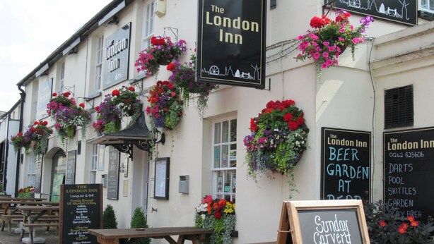 The London Inn with outdoor seating, flower baskets, and a sign for Sunday curry. - London Inn (Cheltenham)