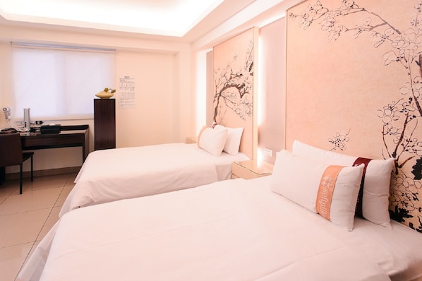 Habitación de hotel con dos camas, un escritorio y un cuadro grande en la pared.