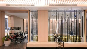 A modern lobby with a seating area, a bike rack, and a view through a decorative partition. - Kiwi Express Hotel - Kaohsiung Station (Kaohsiung)