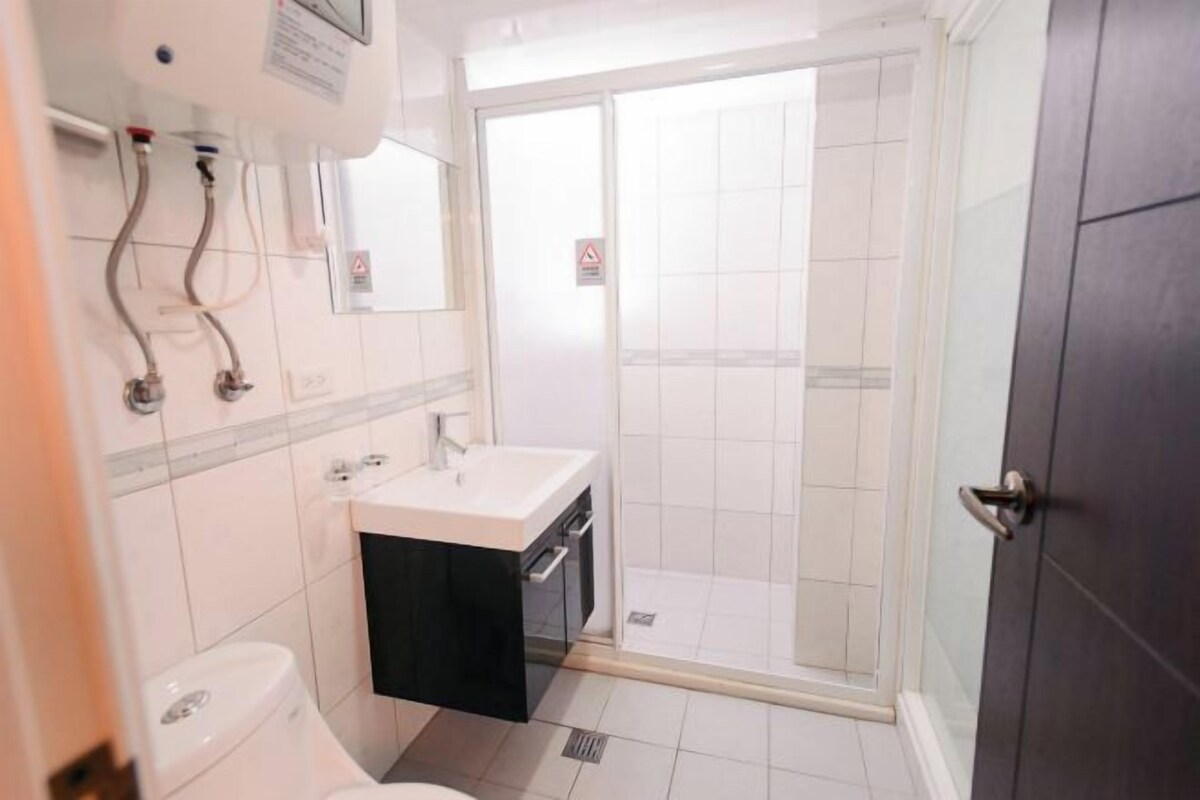A bathroom with a toilet, sink, and shower area.