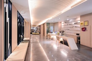 A modern hotel lobby with a sleek design, featuring a long reception desk, comfortable seating areas, and a well-lit ceiling. - Kiwi Express Hotel - Kaohsiung Station (Kaohsiung)