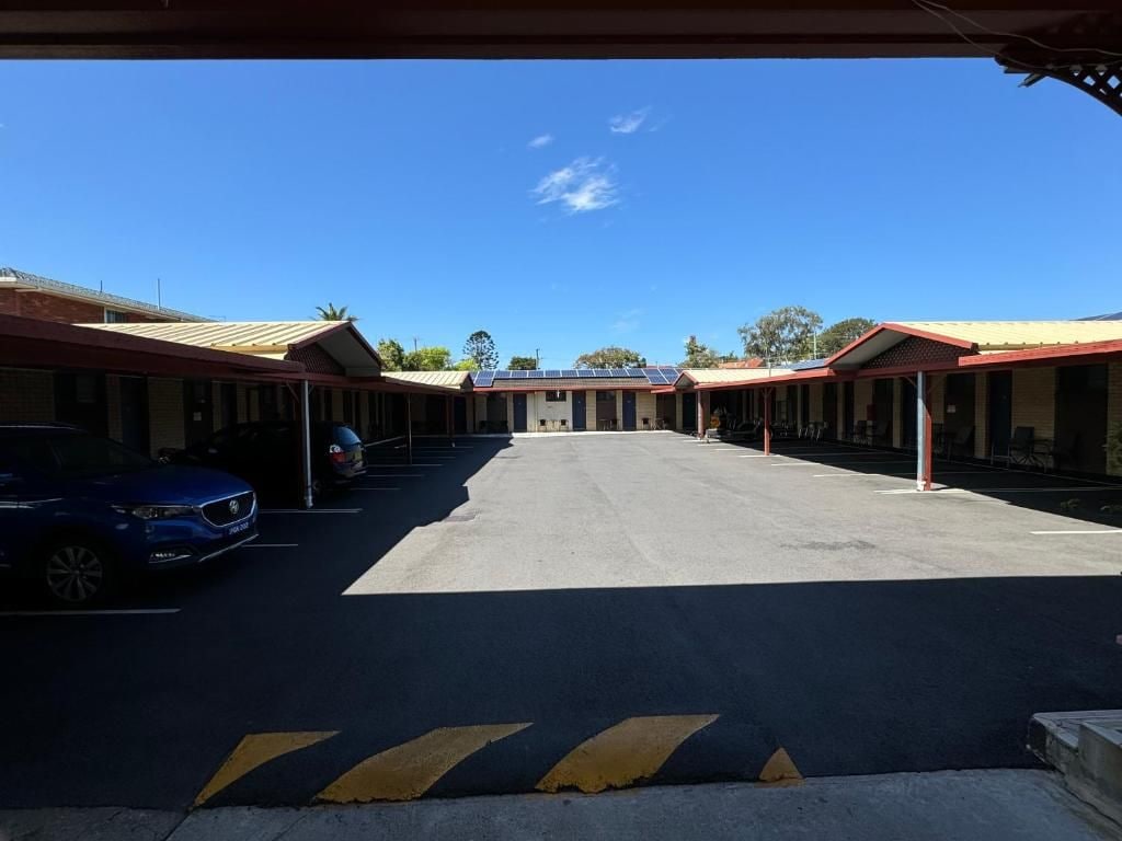 A motel with a central parking area and multiple rooms with red roofs.