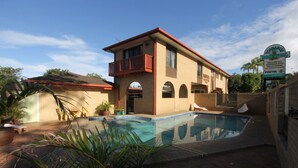 A two-story motel with a swimming pool, a balcony, and a sign indicating pet-friendly accommodations. - Toreador Motel (Coffs Harbour)