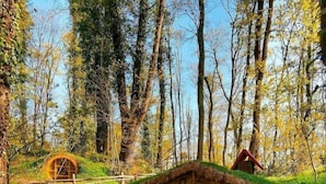 A Hobbit-style house with a round door, stone steps leading up to it, and a table set with a red polka dot tablecloth. - Wellborn Luxury Hotel (Basiskele)
