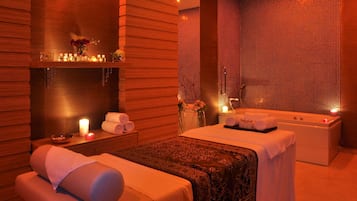 Experience relaxation in this serene spa room featuring a massage table, separate bathtub area, and soothing ambiance.