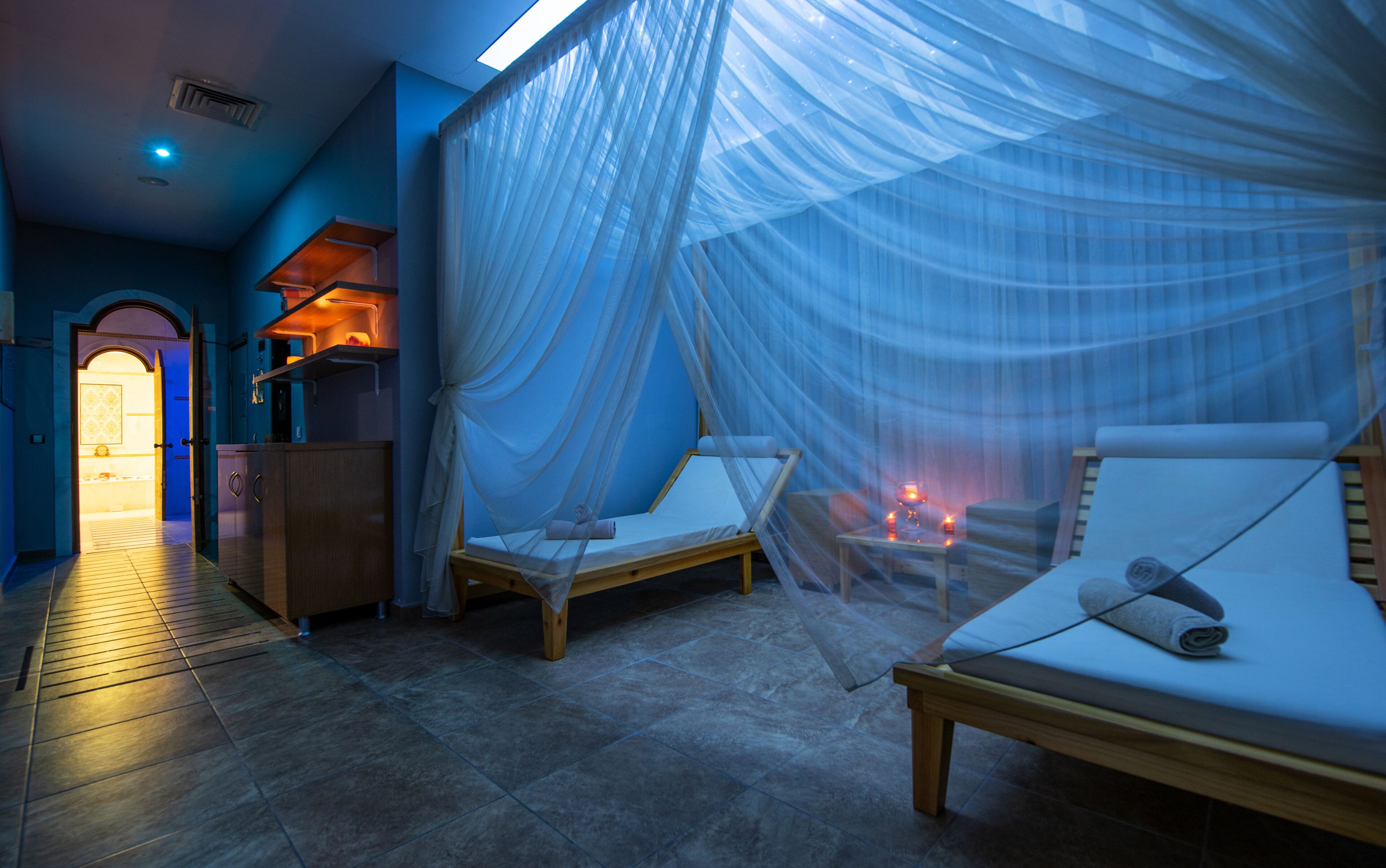 Una habitación con cama, mesita de noche y dosel con cortinas translúcidas.