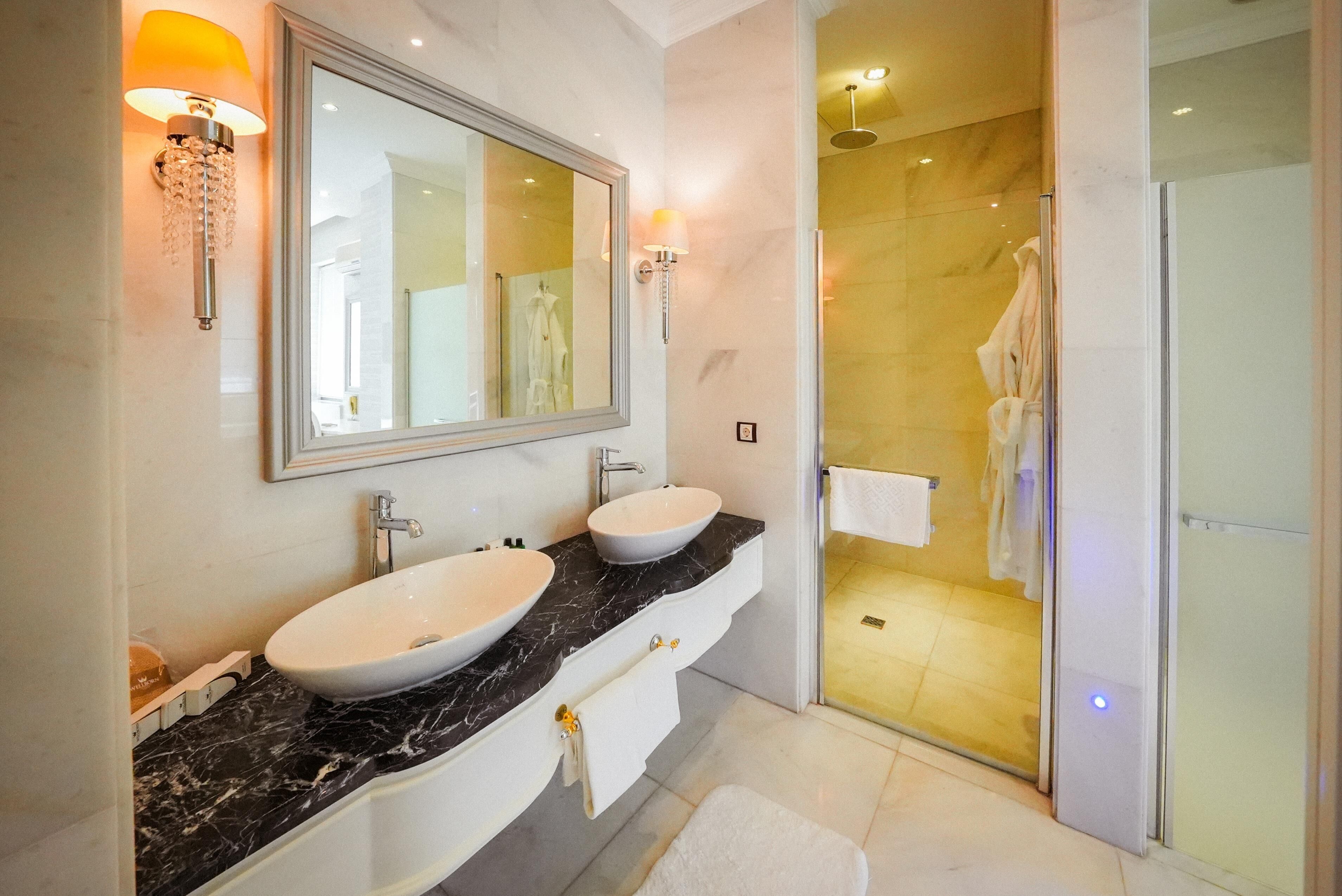 A bathroom with two sinks, a large mirror, and a glass shower enclosure.