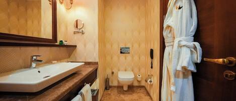 A bathroom with a sink, toilet, and a robe hanging on the door.