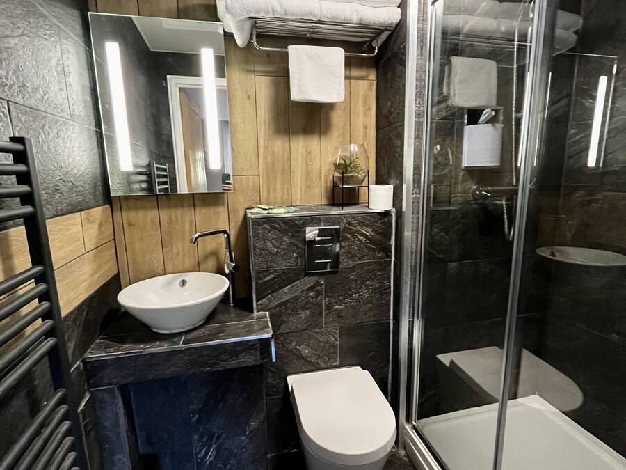 Et moderne badeværelse med brusekabine i glas, vask og toilet.
