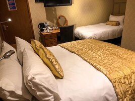 Habitación de hotel con dos camas, un escritorio con espejo, televisión y una mesita con artículos de aseo.