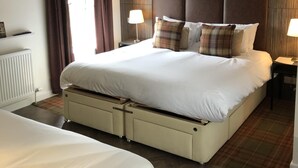 Habitación de hotel con una cama grande, una mesita de noche con lámpara, un radiador y vistas al exterior.