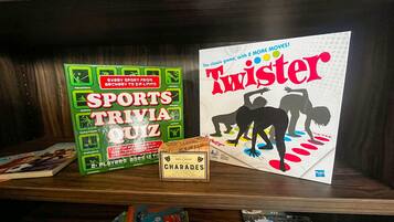 Una estantería con libros y juegos, incluyendo un 'Sports Trivia Quiz' y 'Twister'.